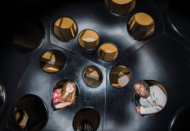 Two people looking inside holes in an immersive art installation in London, UK_to illustrate Academics urged to fill policy void at heart of new UK government