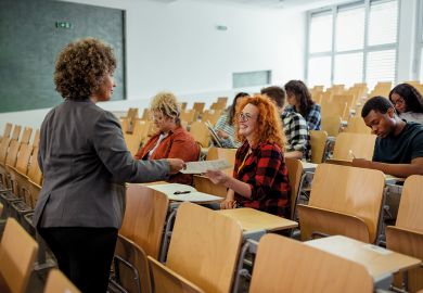 Teacher Handing Over Test Results to Her Students in the Classroom to illustrate I stopped taking class attendance personally – and feel better for it