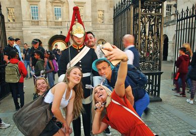 King's guard stands to attention guarding the entrance to the Horse Parade while tourists take a selfie to illustrate Age of the influencer?