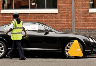 A parking enforcement officer walks past a car with a wheel clamp A parking enforcement officer walks past a car with a wheel clamp to illustrate High impact and low quality linked