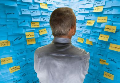 Middle-aged man standing in front of wall covered in sticky notes to illustrate Big HE ideas are plentiful. Why aren’t v-cs listening?
