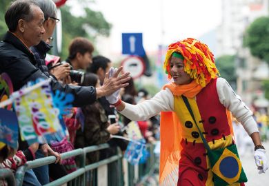 An actor gives a 'hi five' to a spectator in Macao, south China to illustrate ‘We see Macao as a bridge between West and China’