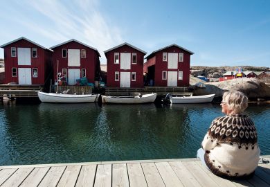 Woman relaxing on jetty and looking at a row of boat houses in Sweden Woman relaxing on jetty and looking at a row of boat houses in Sweden to illustrate Autonomy concerns as Sweden consolidates research funders