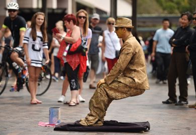 Tourists watch a mime artist perform in Sydney to illustrate Australian vice-chancellors’ pay rises ‘paused’ post-pandemic