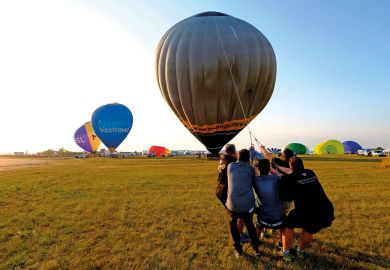 People pull on a rope to lift their hot-air balloon People pull on a rope to lift their hot-air balloon to illustrate Few UK universities raise overseas fees in line with inflation
