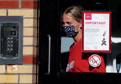 A student leaves one of the accommodation blocks with a Covid sign on the window
