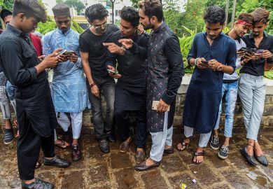 Group of people looking at their phones in Mumbai to illustrate Deadline looms for India’s national academic credit bank