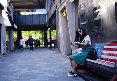 A woman sitting on an empty bench painted in a US flag in Beijing to illustrate Study abroad: US students all but absent from China