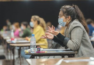 Student wearing mask at the desk in an exam hall as a metaphor for a test of resilience