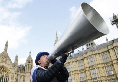 A demonstrator holds up a megaphone  near the Houses of Parliament to illustrate the Free speech bill fans urge ministers to force home right to sue