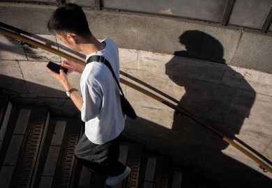 A person using his phone with his shadow on the wall to illustrate  a Dutch helpline for harassed academics gets first reports