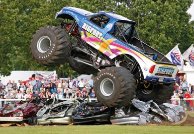 Monster truck driving over cars Monster truck driving over and flattening cars to illustrate DeSantis ‘wants to put trustees in charge of faculty hiring’