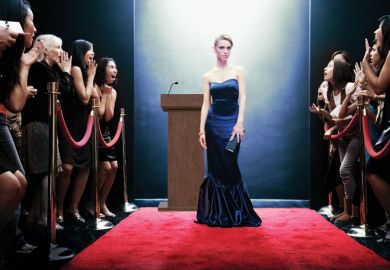 celebrity on red carpet, crowd behind barriers looking excited at seeing her.