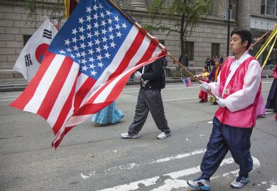 Annual Korean Day Parade man holding American flag Annual Korean Day Parade man holding American flag to illustrate ‘High stakes’ and hurdles ahead for KAIST’s New York campus
