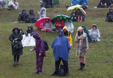 Drenched crowd  in a storm in Glanusk Park, Brecon, Wales, UK to illustrate Medr prepares to tackle financial and participation challenges in Wales