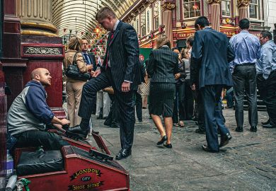 Shoe cleaner is polishing the shoes of a buissnesman in Leadenhall Market to illustrate Academics ‘treat staff like scum’