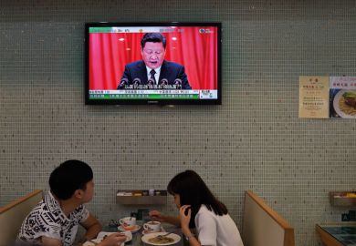  couple eat lunch in a cafe in Hong Kong under a television showing China's President Xi Jinping giving a speech to illustrate Changing of guard in Hong Kong leadership ‘may narrow diversity’