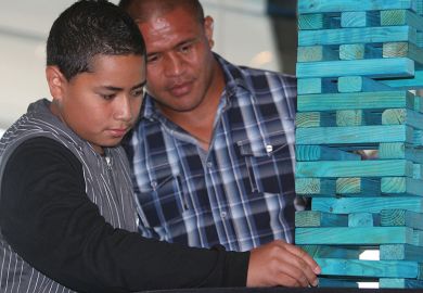 Boy makes a move on a jenga game to illustrate New Zealand mulls introducing base funding for research