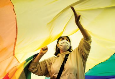 Person standing under an LGBT flag. Person standing under an LGBT flag as a metaphor for Melbourne revises free speech rules over transgender concerns.