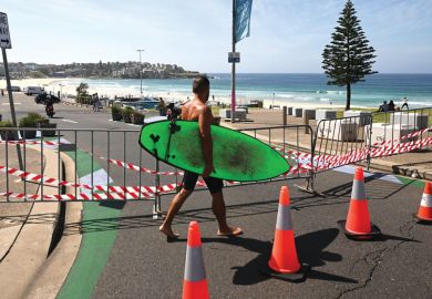 A surfer walks past the entrance to the car park to Bondi Beach which is blocked as a metaphor for research grant veto powers need guidance, say scholars