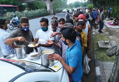 Homeless people queue for food along a road in New Delhi. Homeless people queue for food along a road in New Delhi to show the hardship people have during Covid.