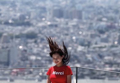 A woman poses for a picture with her hair blown upwards with the Tokyo skyline on the Shibuya Sky observation deck in Tokyo to illustrate ‘Sharp rise’ in science gender quotas at Japanese universities
