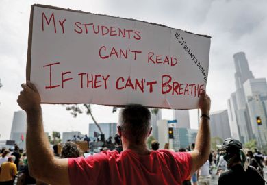 Protestor holding banner reading 'My students can't read If they can't breath for US college students battle alumni as they seek racial equity.