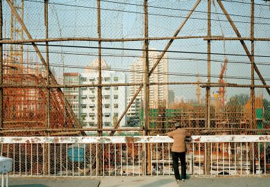 Woman looking down at a construction site, Beijing, China Woman looking down at construction site, Beijing, China to illustrate Chinese universities abandon or repurpose regional campuses