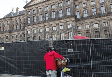 A woman peeks through the fence at the Royal Palace, Netherlands to illustrate Amsterdam ‘experiment’ with language caps ‘legally risky’