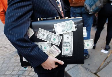 A protester dressed as a businessman, holds a briefcase covered in U.S. dollar notes A protester dressed as a businessman, holds a briefcase covered in U.S. dollar notes to illustrate Stanford law school trials income-based student loans