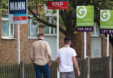 Pedestrians walk past estate agents' 'Let By', 'Sold', and 'For Sale' signs