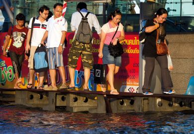 Bangkok commuters head home negotiating a narrow walkway through heavily flooded downtown streets