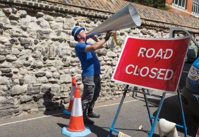 Man shouts through his oversized megaphone with stop road sign in front of him to illustrate English free speech bill stalls but ministers ‘remain committed