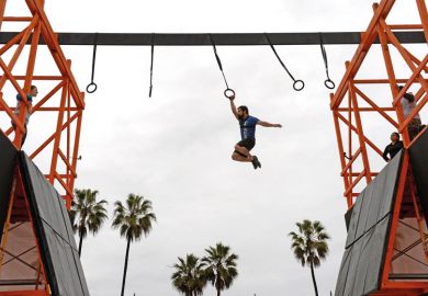 man swings across obstacle course