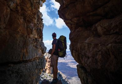 Hiker observes view from gap in rocks