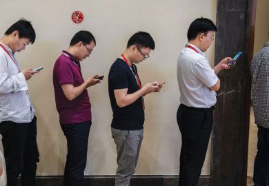 look at their smartphones as they line-up row of men look at their smartphones