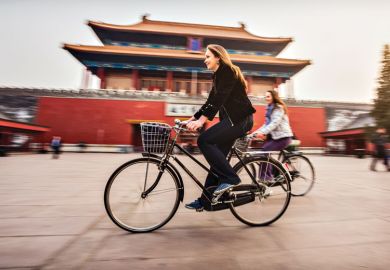 Friends riding retro bicycles along forbidden city Friends riding retro bicycles along forbidden city