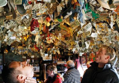 People looking up at pinned mementos left on the ceiling.