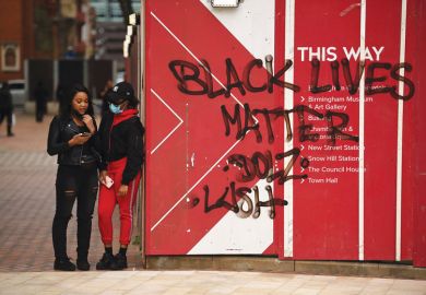 two people stand stand beside Black Lives Matters graffiti 