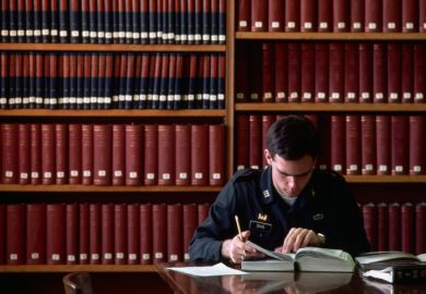 A West Point student reads a book in the library