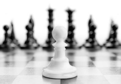 White chess pawn with black pieces in background White chess pawn with black pieces in background