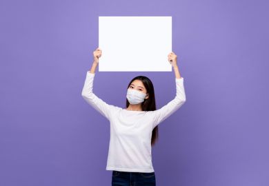 An Asian woman holds up a blank piece of paper