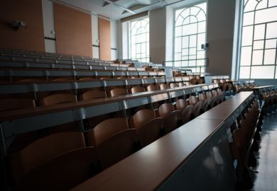 Wide angle shot of a university classroom with rows of chairs and desks
