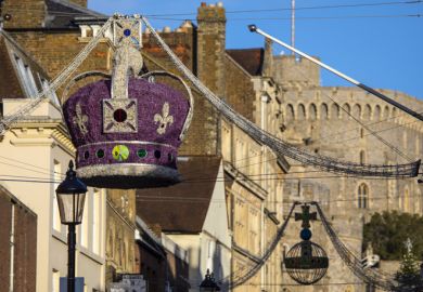 Windsor, UK - November 28th 2021 A Royal Crown Christmas decoration in the town centre of Windsor, with Windsor Castle in the background, in Berkshire, UK.