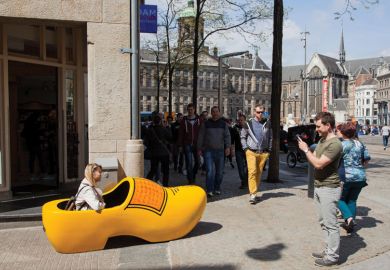 Woman sitting in giant yellow clog
