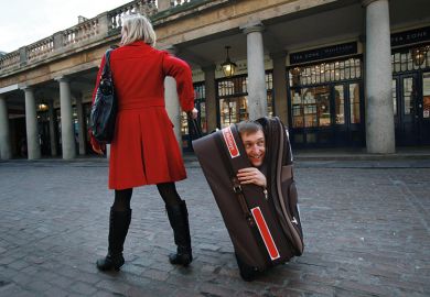 woman pulling along man hidden in suitcase