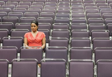 Woman sitting alone on empty lecture hall Woman sitting alone on empty lecture hall