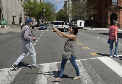 Woman using smartphone selfie stick while crossing road