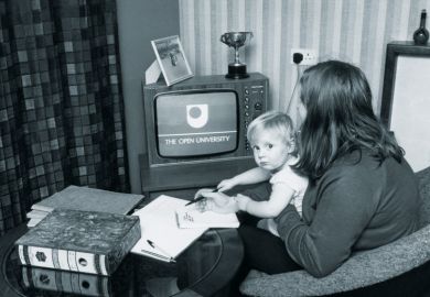Woman watching The Open University on TV while holding child Woman watching The Open University on TV while holding child