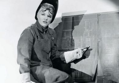 Woman wearing protective clothing pointing at blueprints